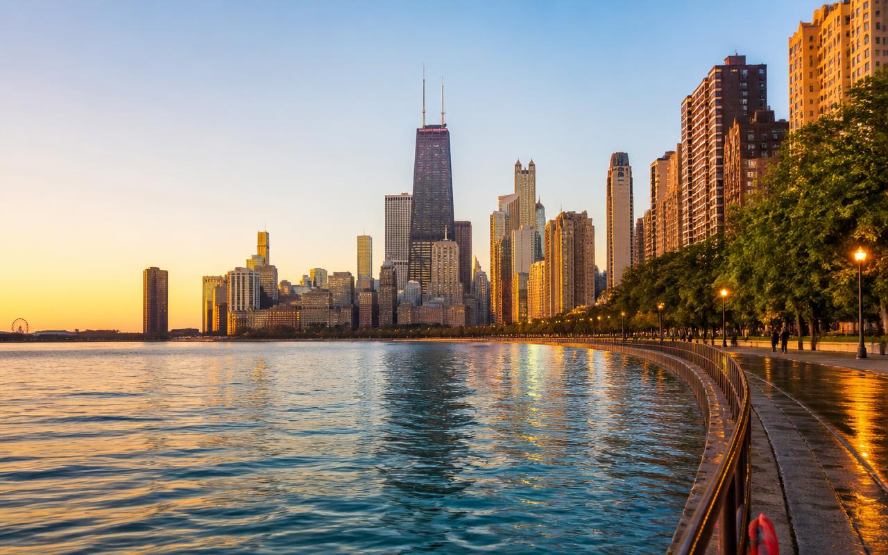 Chicago skyline and lakefront path at golden hour seen across Lake Michigan